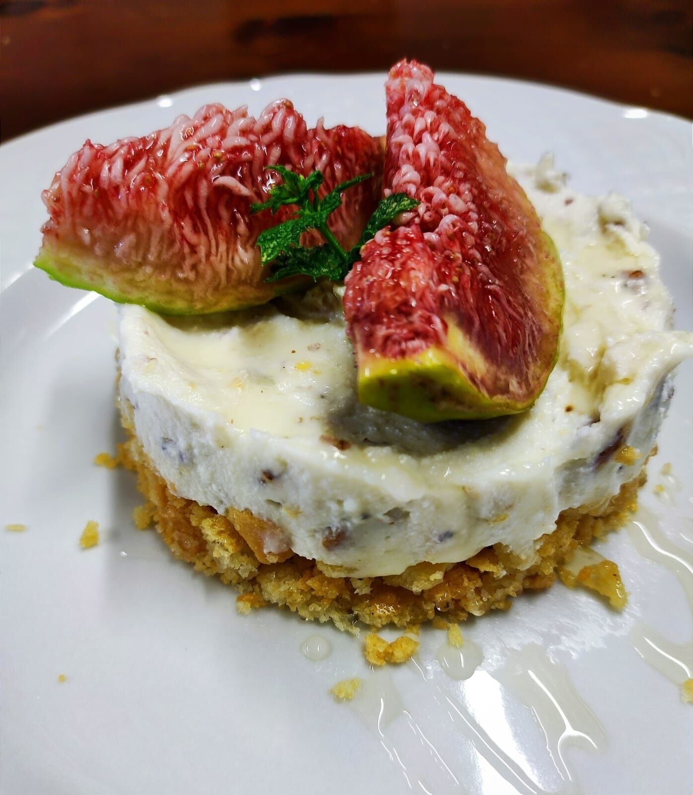 A dessert with a creamy base, topped with a fruit slice and a mint leaf.
