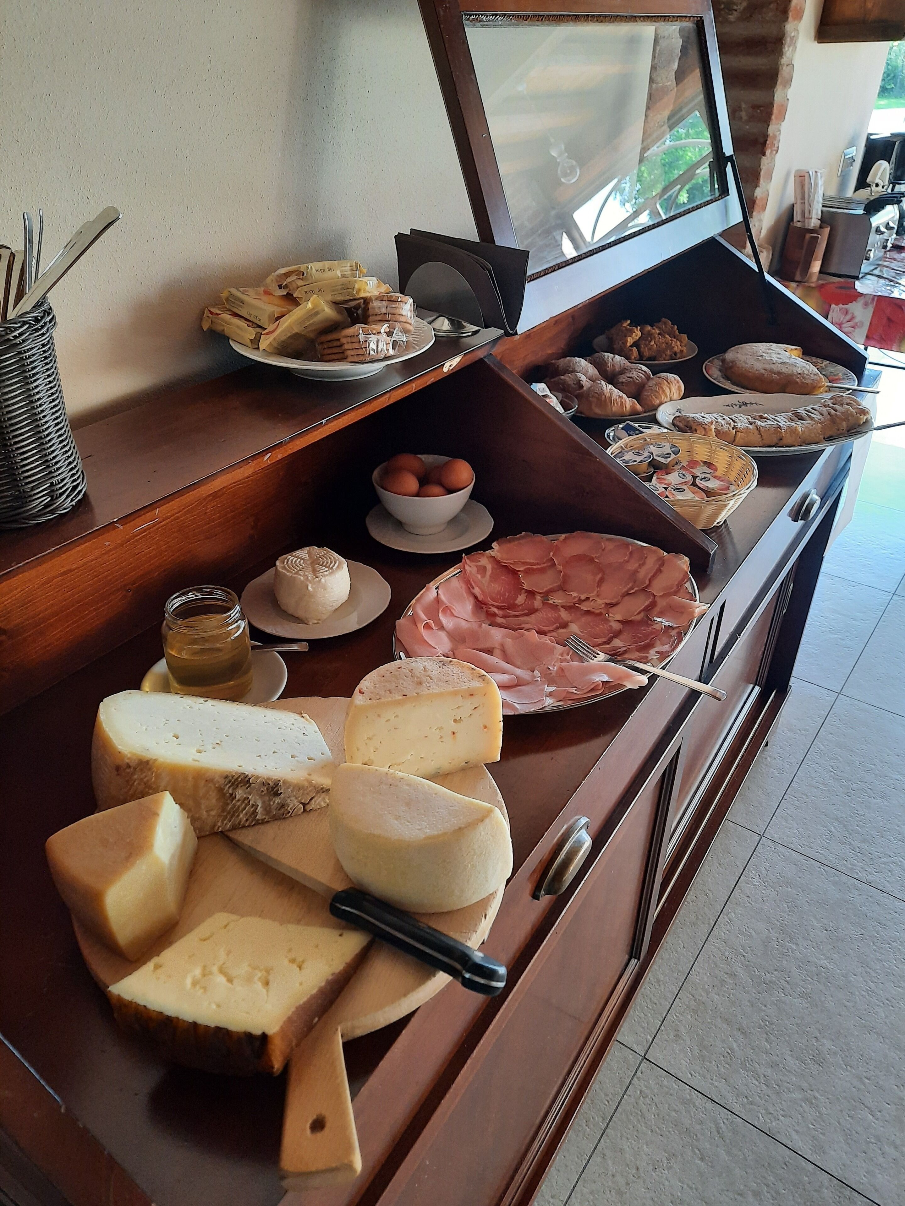 Un bufé con varios quesos, carnes y pasteles.