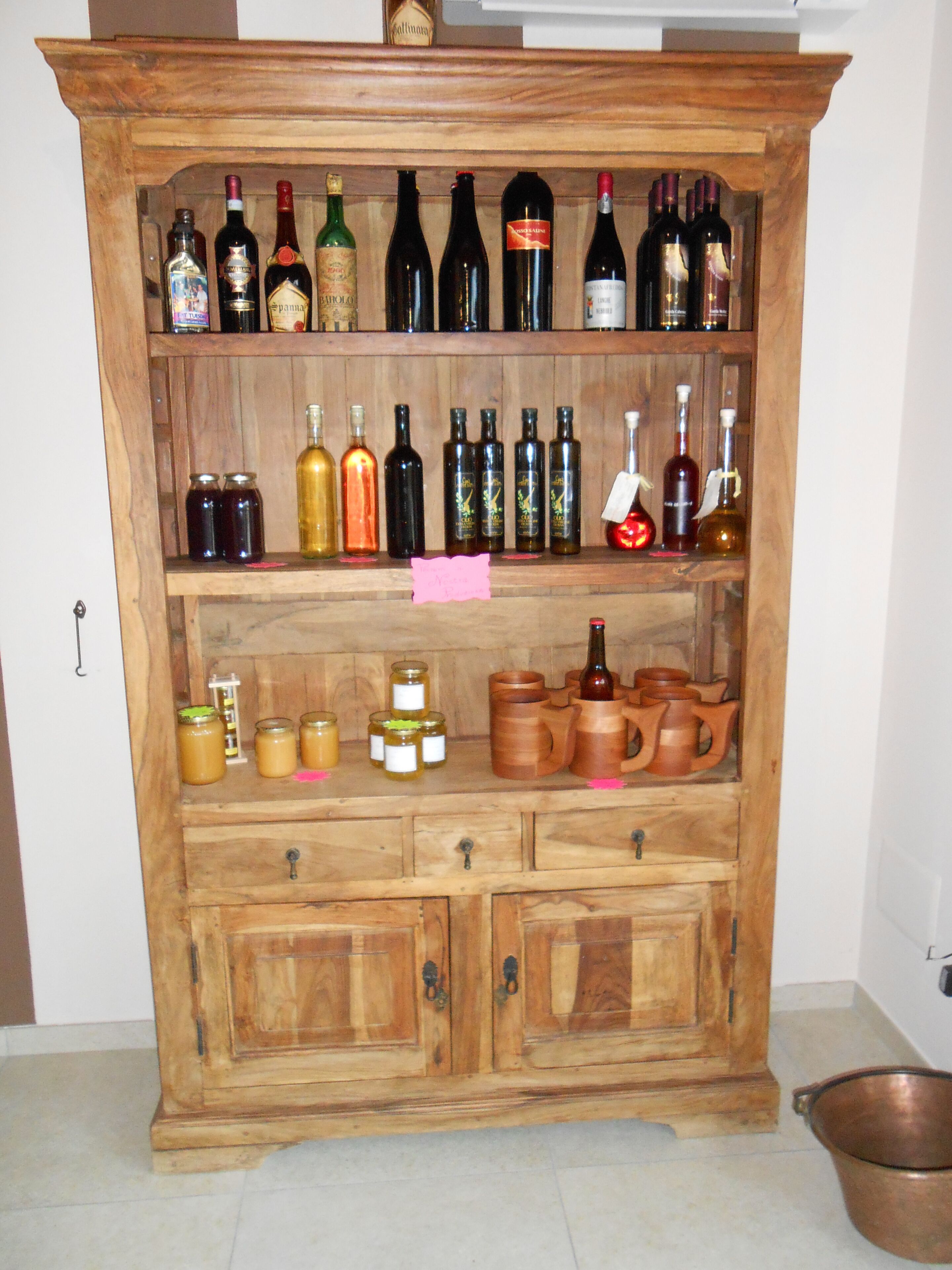 Un mueble de madera con varios estantes que contiene botellas y frascos.
