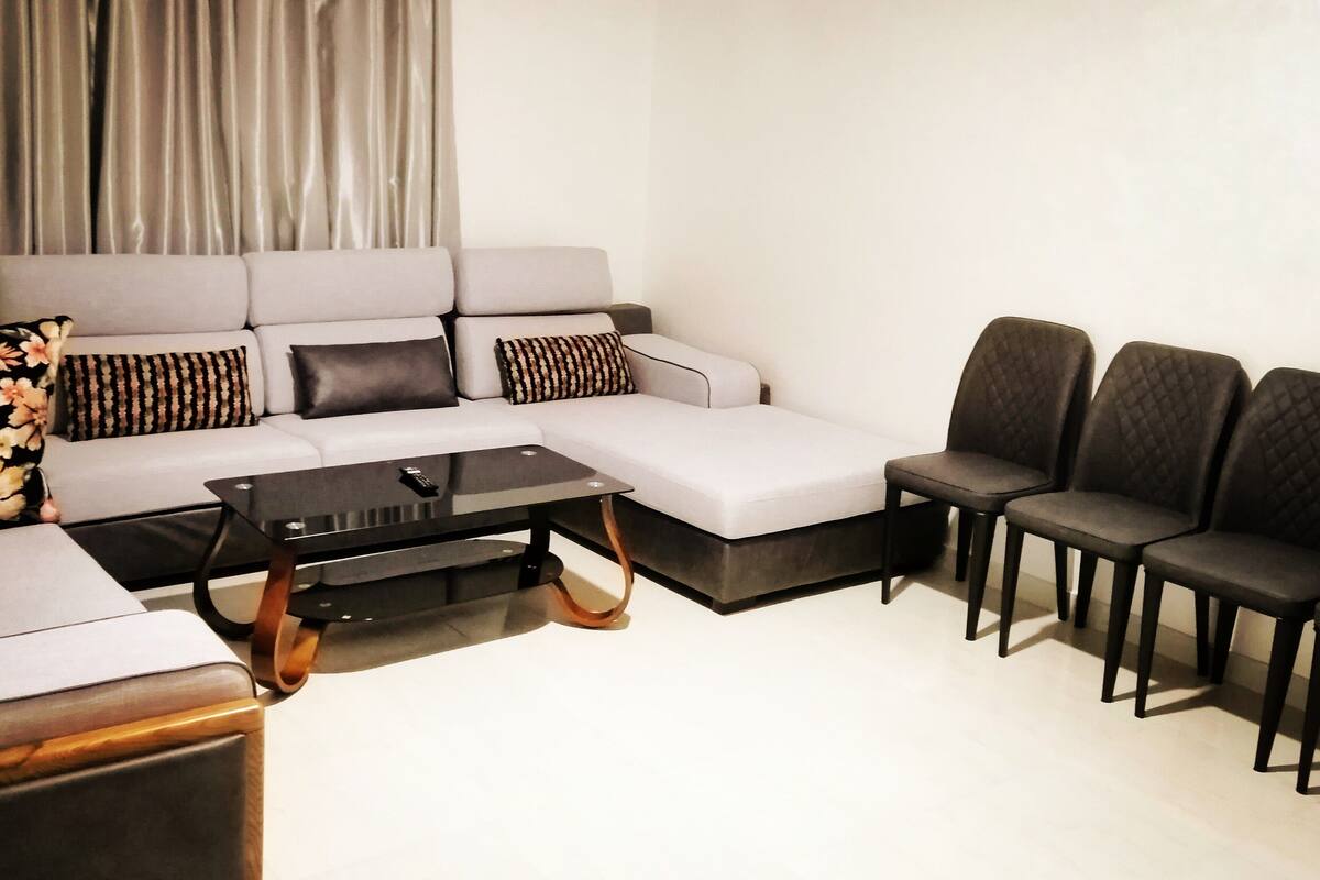 A modern living room with a sectional sofa, a coffee table, and a set of chairs.