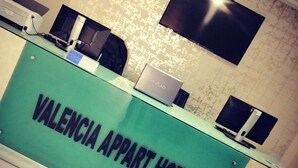 Een receptiebalie bij Valencia Appart Hotel, met een marmeren vloer en een betegelde muur.