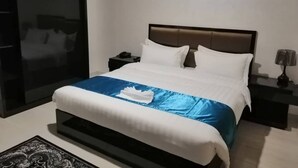 Een moderne hotelkamer met een groot bed, een nachtkastje, een lamp en een stadszicht door een groot raam.