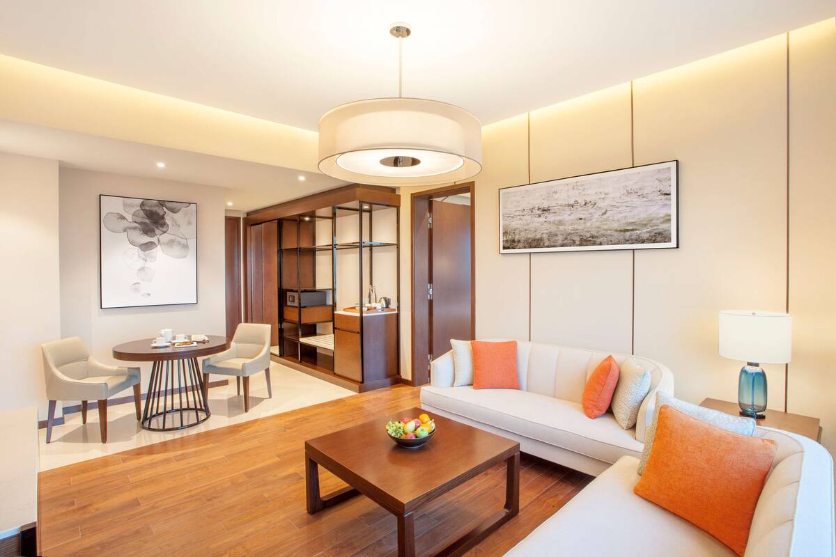 Una sala moderna con una mesa de centro de madera, un sofá blanco y sillas color beige.
