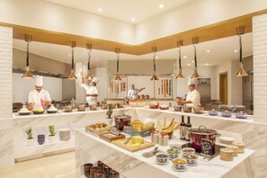 A modern kitchen with chefs preparing food, marble countertops, and various food items displayed. - Hyatt Regency Thrissur (Thrissur)