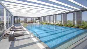 Una piscina en la azotea con tumbonas y vistas del horizonte urbano.