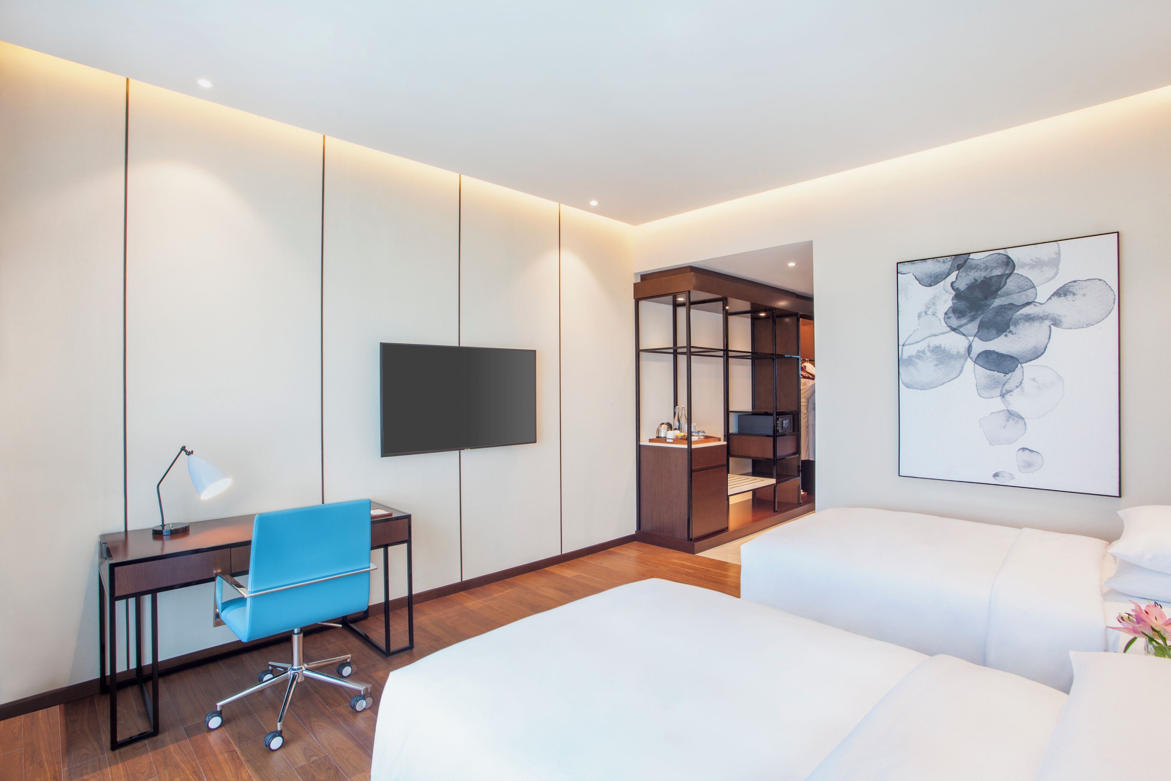 A hotel room with a bed, a desk, a chair, a television, and a wardrobe.