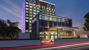 Un hotel moderno con una fachada de vidrio destacada, una entrada bien iluminada y un letrero visible que dice "HYATT REGENCY".