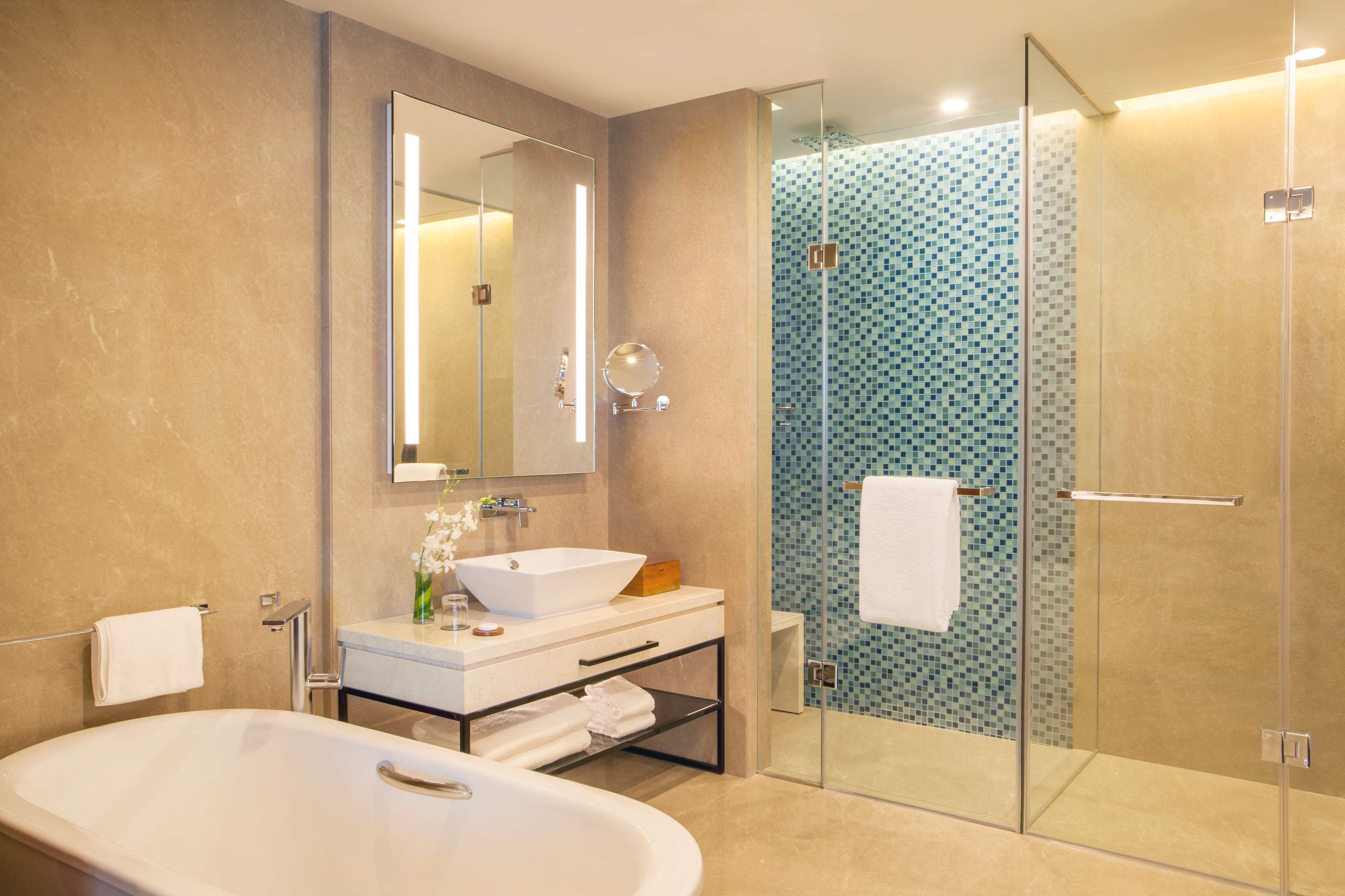 A modern bathroom with a freestanding bathtub, a large mirror, a glass-enclosed shower, and a tiled backsplash.