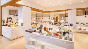 Zona de bufé con distintas estaciones de comida, que incluyen jugos frescos, ensaladas y postres.