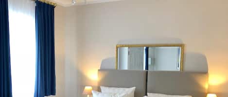 A hotel room with a large bed, a chandelier, a mirror, and a bedside lamp.