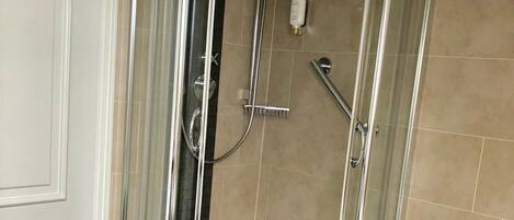 Mampara de ducha de esquina con puerta de cristal y dos duchas de mano.