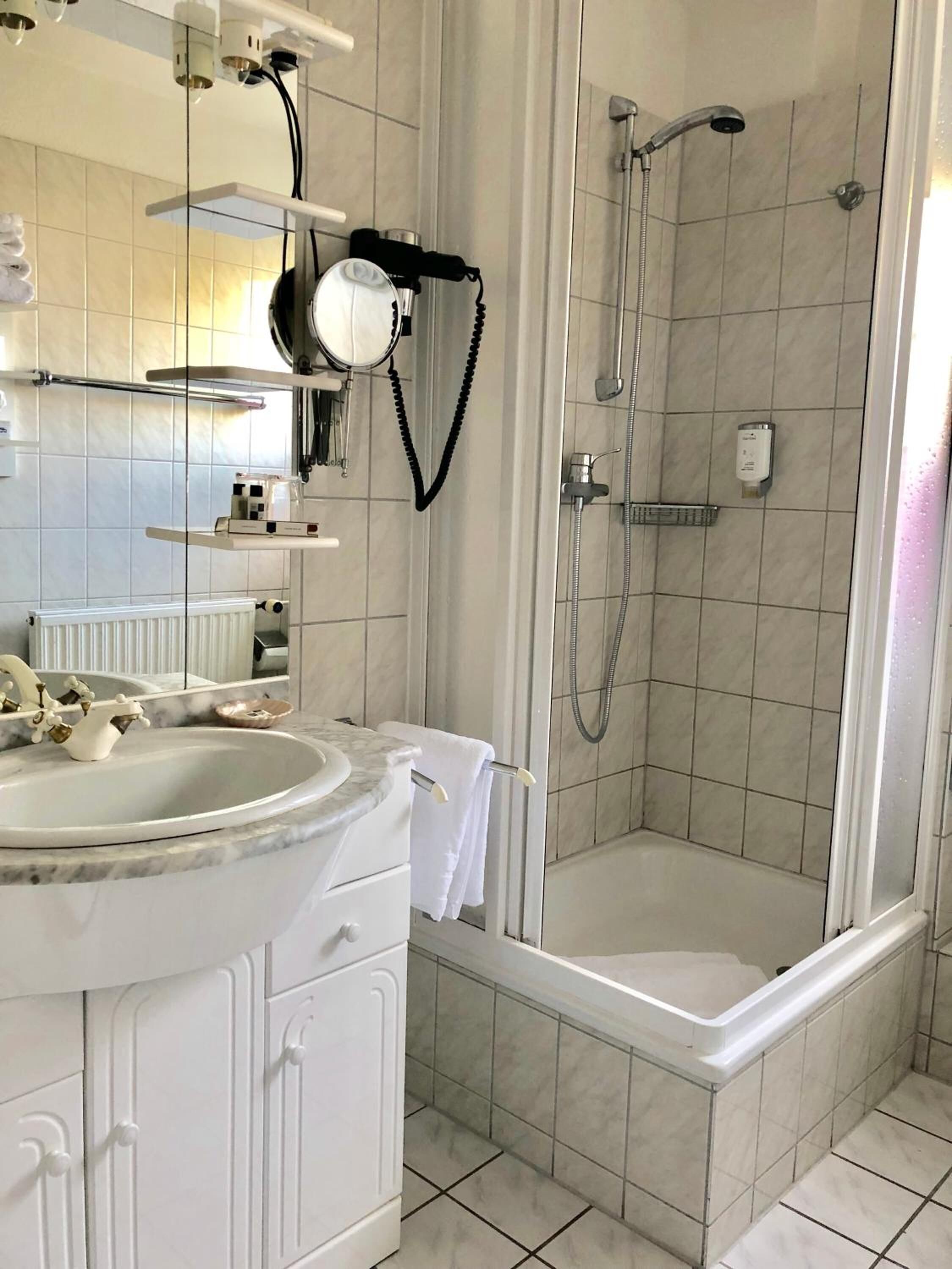 A modern bathroom with a bathtub, a shower, a sink with a marble countertop, and a mirror.