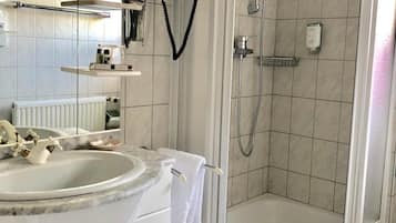 A modern bathroom with a bathtub, a shower, a sink with a marble countertop, and a mirror.
