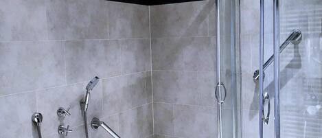 Uma casa de banho moderna com chuveiro envolto em vidro, banheira independente e uma faixa preta que percorre a parede horizontalmente.