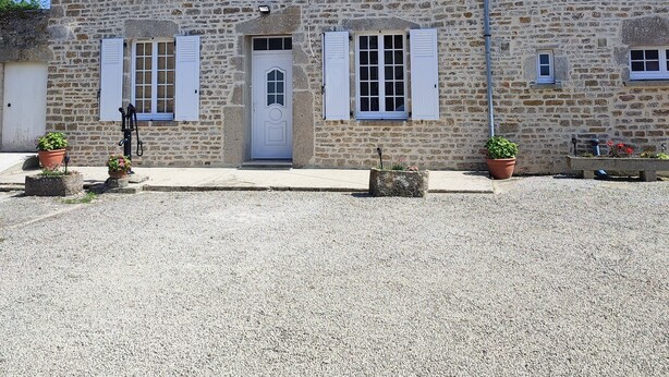 A stone building with a symmetrical facade, a central entrance with a door, and multiple windows with shutters.