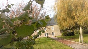 A stone building with a well-maintained lawn and a tree with yellow leaves.