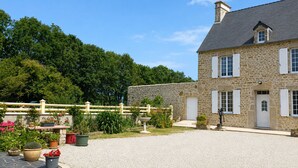 A stone building with a gravel driveway, a wooden fence, and potted plants.