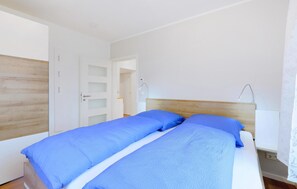 A bedroom with a bed, a wooden headboard, a white door, and a nightstand with a lamp. - 1 bedroom nice apartment in Rechlin (Rechlin)