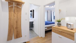 A modern bedroom with a wooden wardrobe, a bedside table with a lamp, and a view into the bathroom. - 1 bedroom nice apartment in Rechlin (Rechlin)