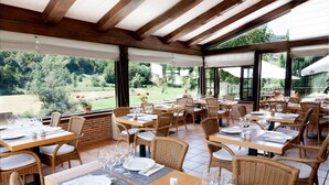 An outdoor dining area with wicker furniture, tables set with plates and glasses, and a view of a green landscape. - Paraíso del Bierzo (Vega de Valcarce)
