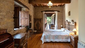 A rustic bedroom with a wooden bed, a desk, and a stone wall. - Paraíso del Bierzo (Vega de Valcarce)