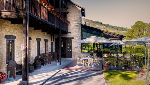 A stone building with outdoor seating and a glass enclosure. - Paraíso del Bierzo (Vega de Valcarce)