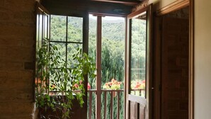 A wooden interior with a large window leading to a balcony with a view of greenery. - Paraíso del Bierzo (Vega de Valcarce)