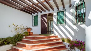 Un escalier extérieur mène à une porte marron, dont les encadrements de fenêtre sont verts.