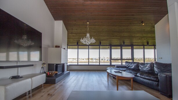 Una sala de estar moderna con televisor grande, sofá de cuero y una mesa de centro de madera.