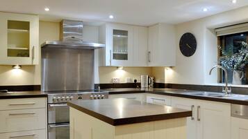 Een moderne keuken met een centraal eiland, roestvrijstalen apparatuur en een klok aan de muur.