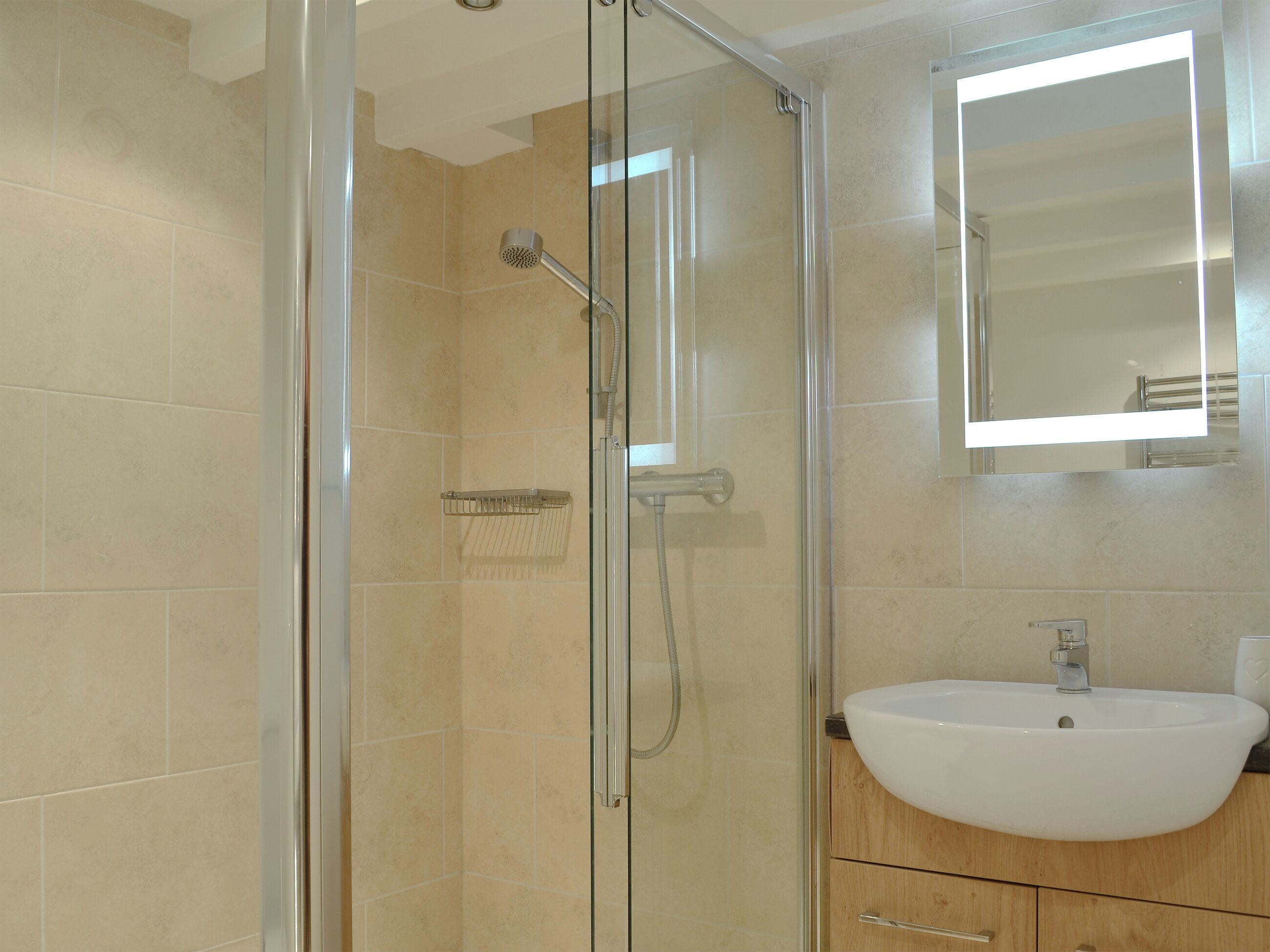 A modern bathroom with a glass-enclosed shower, a white sink, and a mirror above the sink.