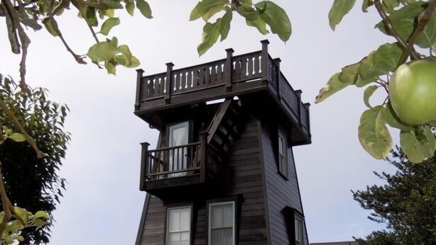 Une maison dotée d’une architecture originale, avec une structure en forme de tour surmontée d’un balcon.