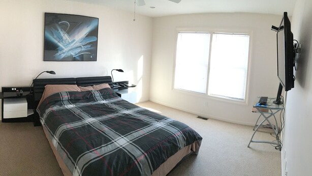 Un dormitorio con cama, escritorio, silla, televisor y ventana.