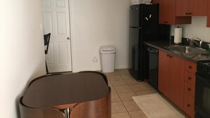 Una cocina compacta con refrigerador, estufa, lavamanos y basurero.