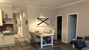 A modern kitchen with white cabinets, a dining table with four chairs, and a pendant light. - Luxurious apartment for 4 persons with parking directly in front of the terrace (Kühlungsborn-West)