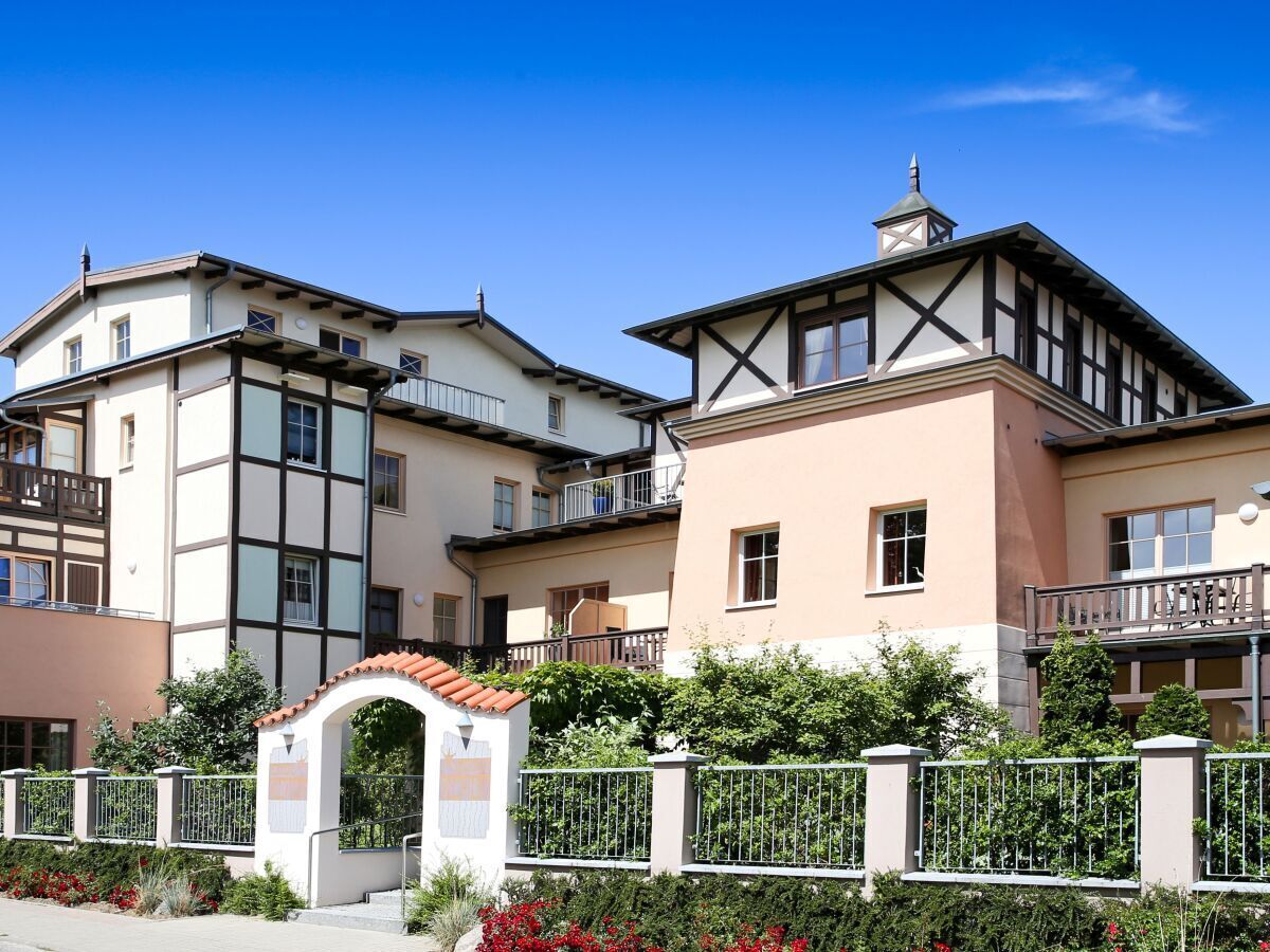 Une rangée d’immeubles modernes à plusieurs étages, dotés de balcons, d’une entrée sécurisée et d’une petite arche.