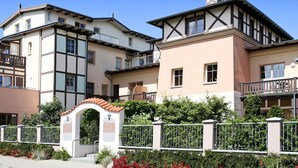 A row of modern multi-story buildings with balconies, a gated entrance, and a small archway. - Luxurious apartment for 4 persons with parking directly in front of the terrace (Kühlungsborn-West)