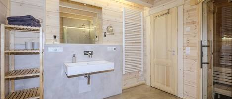 Une salle de bain moderne avec un intérieur en bois, un lavabo, un miroir et un porte-serviettes.