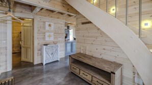 A wooden interior with a staircase, a kitchen area, and a dining space. - Bergwaldlodge Einklang (Wernigerode)