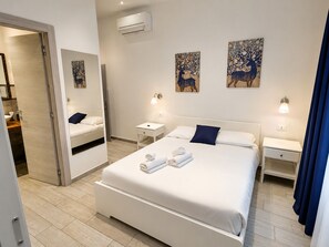 A modern hotel room with a large bed, two bedside tables, a mirror, and artwork on the walls. - ROSSETTI ROOMS (Trieste)
