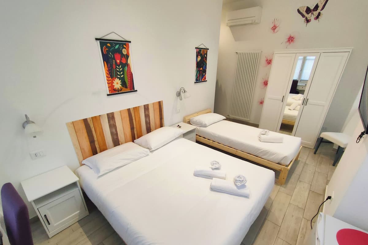 Hotellihuone, jossa on kaksi sänkyä, työpöytä, tuoli ja peili.