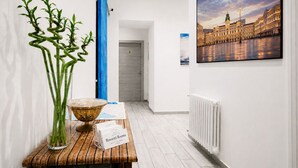 A hotel reception area with a reception desk, a large window with a view of a building, and a framed picture on the wall. - ROSSETTI ROOMS (Trieste)