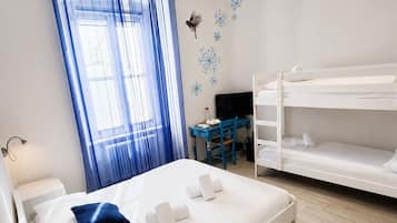 Una habitación de hotel con cama, escritorio, literas y ventana con cortinas.