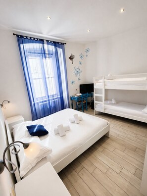 Una habitación de hotel con cama, escritorio, literas y ventana con cortinas.