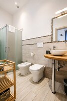Un bagno moderno con box doccia, bidet, lavabo e mobile bagno in legno.