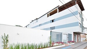Un edificio moderno de dos plantas con fachada blanca y líneas horizontales azules.