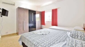 Un dormitorio con cama, armario y televisor montado en la pared.