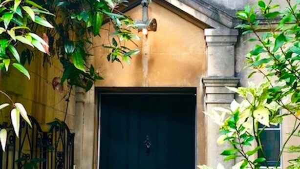 A black door with the number 56, a small step leading up to it, and a metal gate to the left.