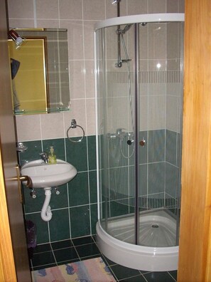 A bathroom with a shower, sink, and mirror.