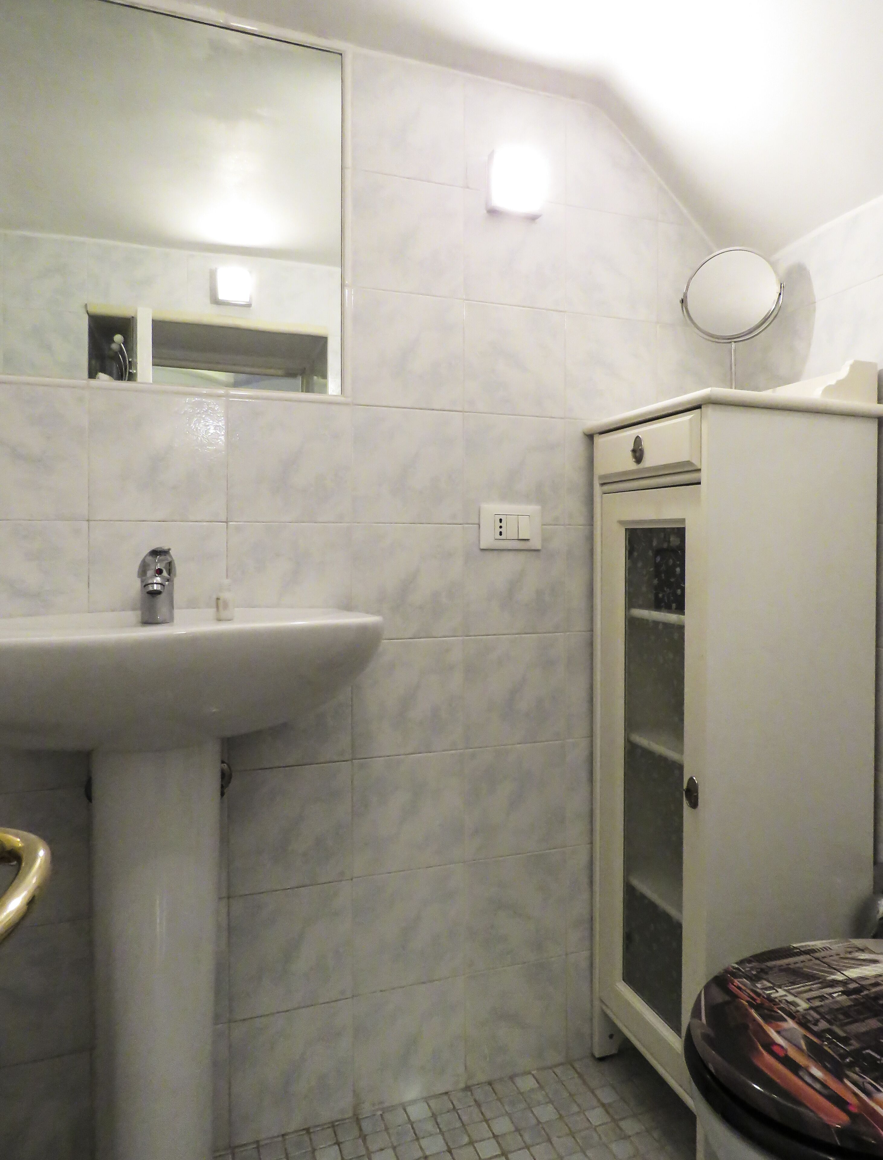 A bathroom with a white sink, a mirror, a cabinet, and a toilet.